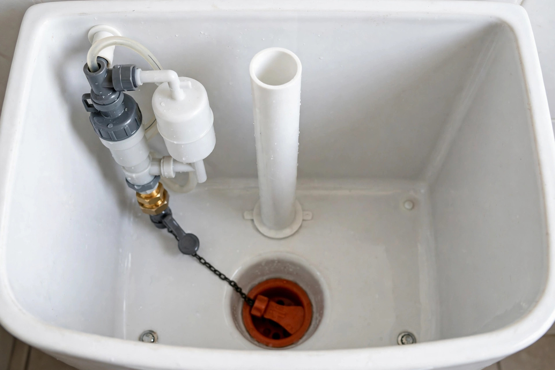 Inside a toilet tank showing the fill valve, flapper, float and overflow tube